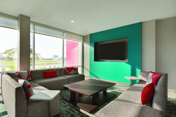 Una sala de estar moderna con un conjunto de sofá, una mesa de centro y un televisor de pantalla plana montado en una pared verde azulado.