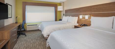 Habitación de hotel con dos camas, un escritorio, una silla, un televisor y una ventana con persianas.