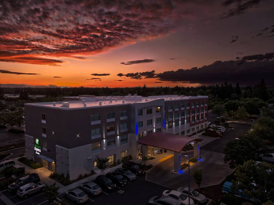 Un hotel con techo plano, varios espacios de estacionamiento y un área exterior cubierta.