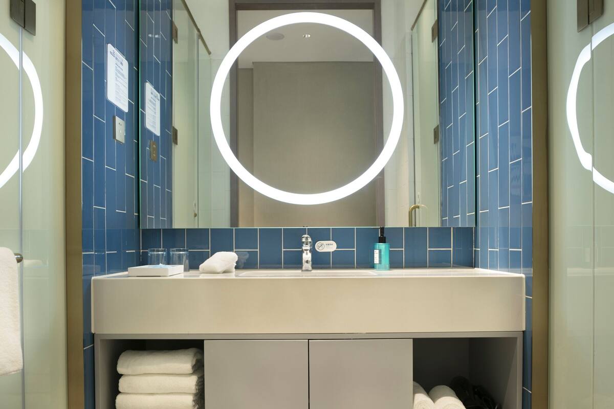 A modern bathroom with a large mirror, a sink, and a towel rack.