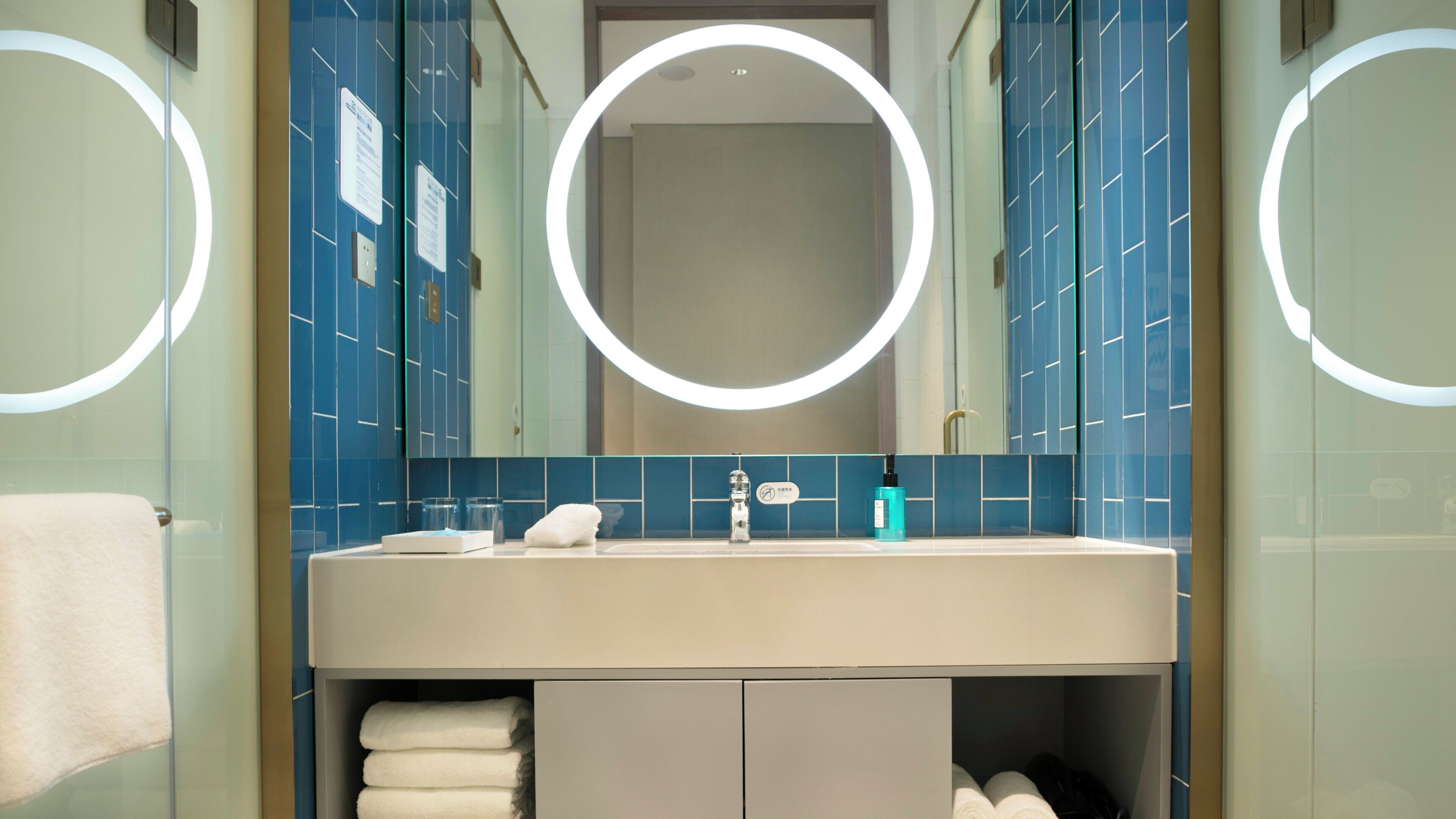A modern bathroom with a large mirror, a sink, and a towel rack.