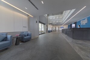 A spacious lobby with a reception desk, seating area, and a high ceiling with skylights. - Holiday Inn Express Beijing Badaling by IHG (Yanqing)