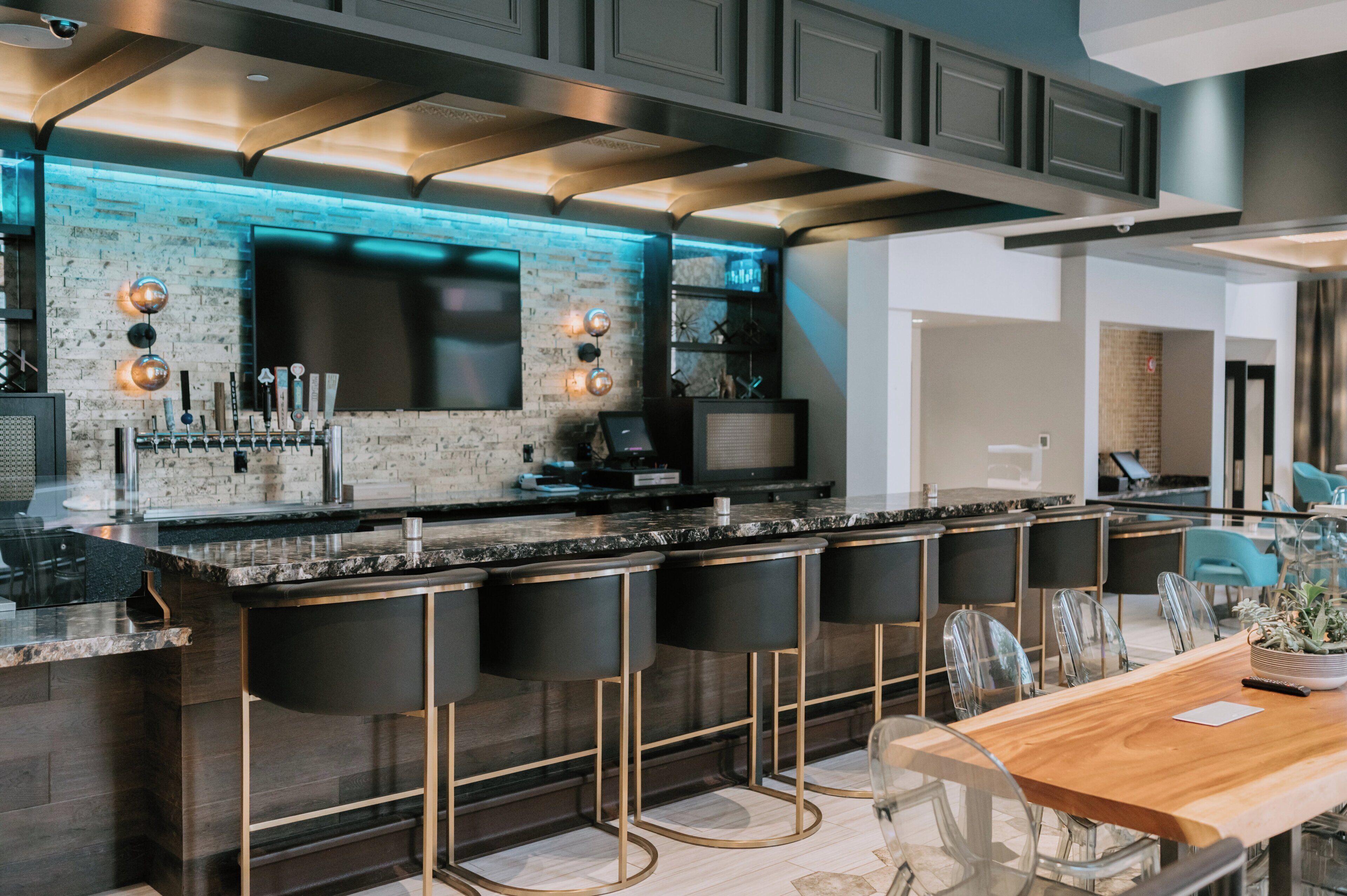 A modern kitchen with a bar area, bar stools, and a dining table with chairs.
