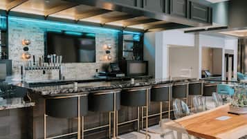 A modern kitchen with a bar area, bar stools, and a dining table with chairs.