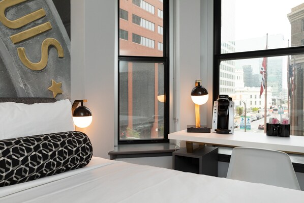 A hotel room with a bed, a desk with a coffee maker, and a window with a city view. - Hotel Indigo St. Louis - Downtown by IHG (St. Louis)