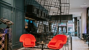 A modern interior with a staircase, red chairs, and a bar area.