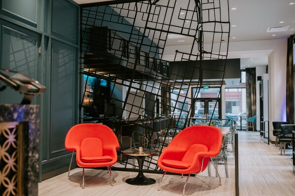 A modern interior with a staircase, red chairs, and a bar area. - Hotel Indigo St. Louis - Downtown by IHG (St. Louis)