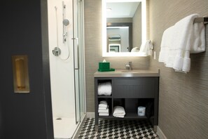 A modern bathroom with a glass shower enclosure, a sink with a mirror, and a towel rack. - Hotel Indigo St. Louis - Downtown by IHG (St. Louis)