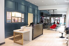 A reception area with a counter, framed artwork on the wall, and a staircase in the background. - Hotel Indigo St. Louis - Downtown by IHG (St. Louis)