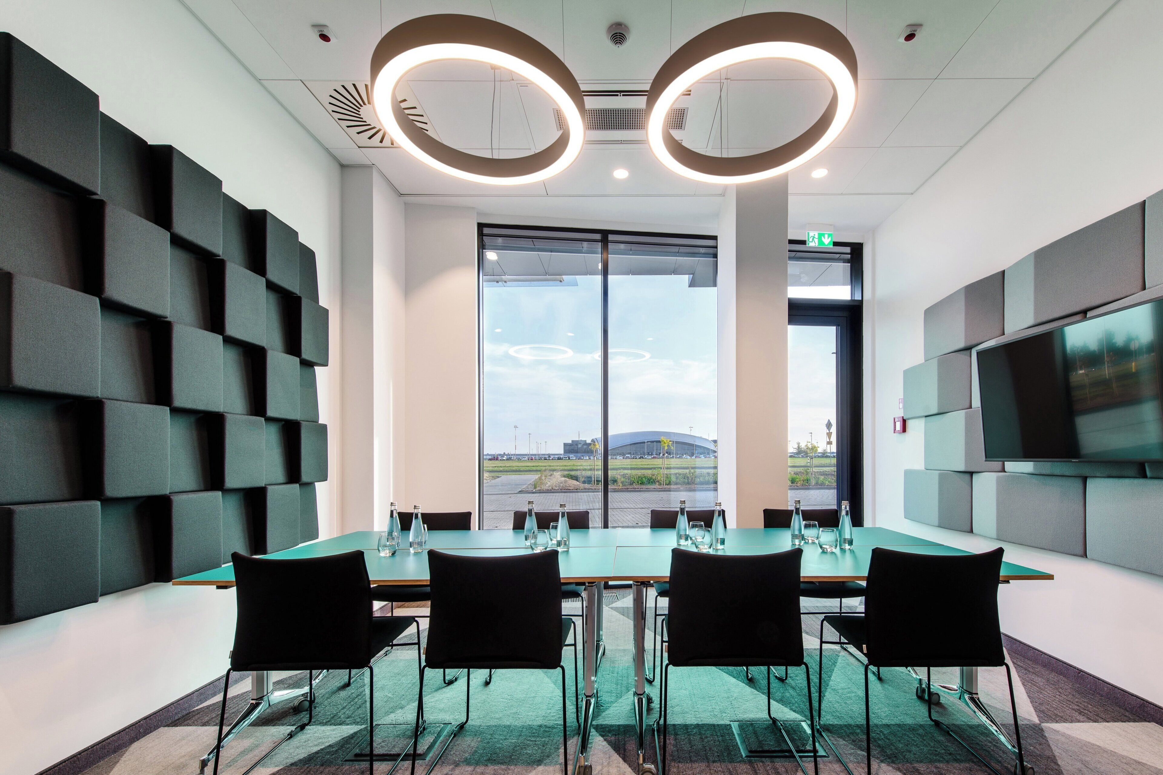 A conference room with a large table, chairs, and a TV screen.
