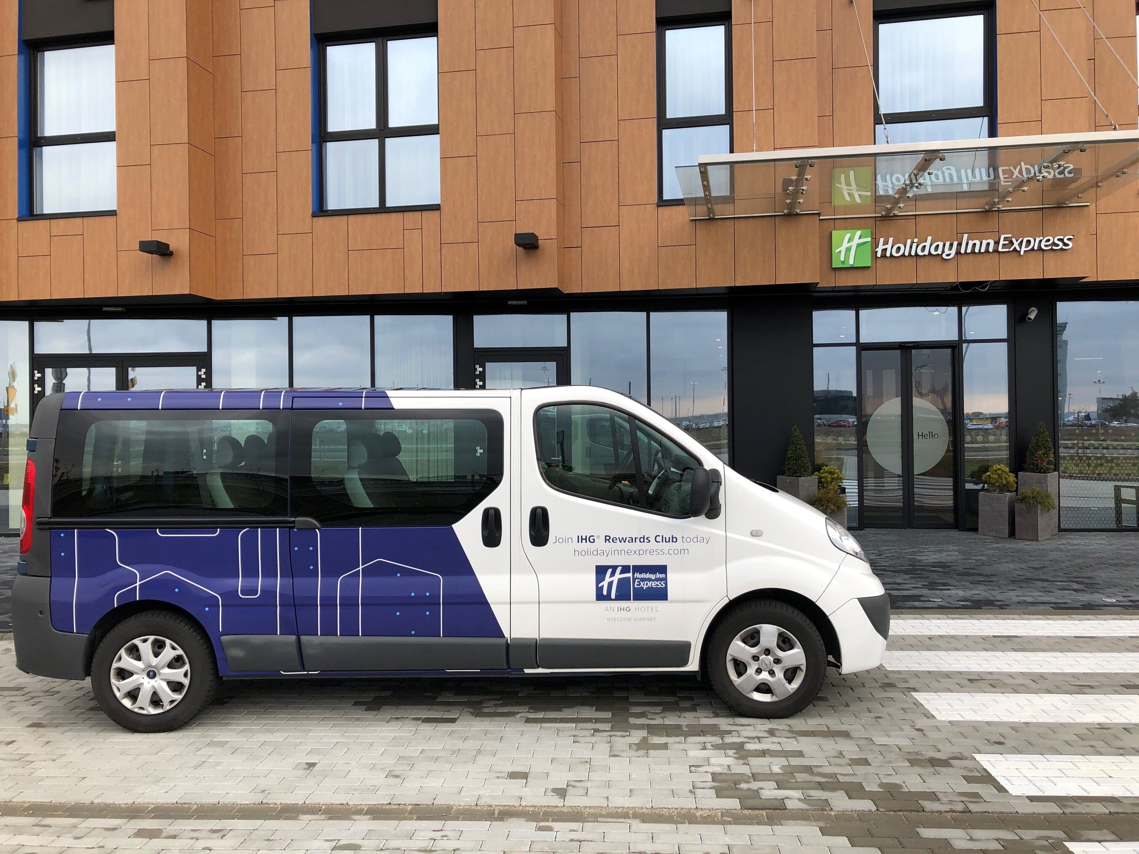 A Holiday Inn Express hotel with a modern facade, a van parked in front, and a clear view of the entrance.