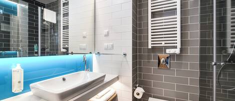 A modern bathroom with a large sink, mirror, towel rack, toilet, and shower.
