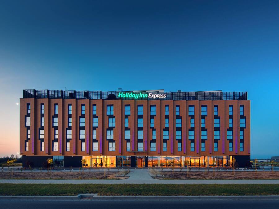 Un hotel Holiday Inn Express con un diseño arquitectónico moderno, que presenta una señalización destacada y una fachada simétrica.