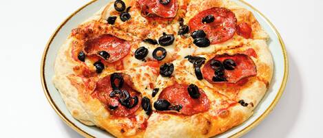 A pizza with pepperoni and black olives on a plate.