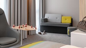 Una sala moderna con un sofá gris, una pequeña mesa de madera con figuritas, y un sillón gris.