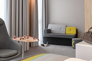 Una sala moderna con un sofá gris, una pequeña mesa de madera con figuritas, y un sillón gris.