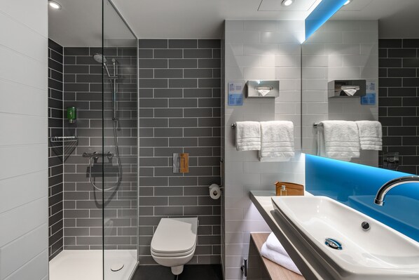 Une salle de bain moderne avec une douche à parois de verre, des toilettes blanches et un lavabo agrémenté d’une touche de bleu.