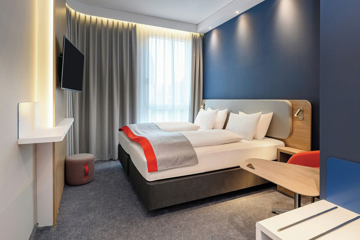 Une chambre d’hôtel moderne équipée d’un lit, d’une télévision, d’un bureau et d’une chaise.