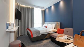 Ein modernes Hotelzimmer mit Bett, Sitzecke und Flachbildfernseher.