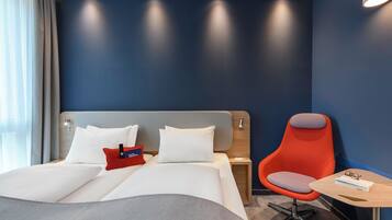 Une chambre d’hôtel avec un lit, une table de chevet, une chaise rouge et une petite table.