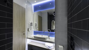 Un baño moderno con un espejo grande, un lavamanos y un perchero para toallas.