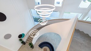 A modern interior with a curved staircase, a circular seating area, and a unique lighting fixture. - Holiday Inn Express Regensburg by IHG (Regensburg)
