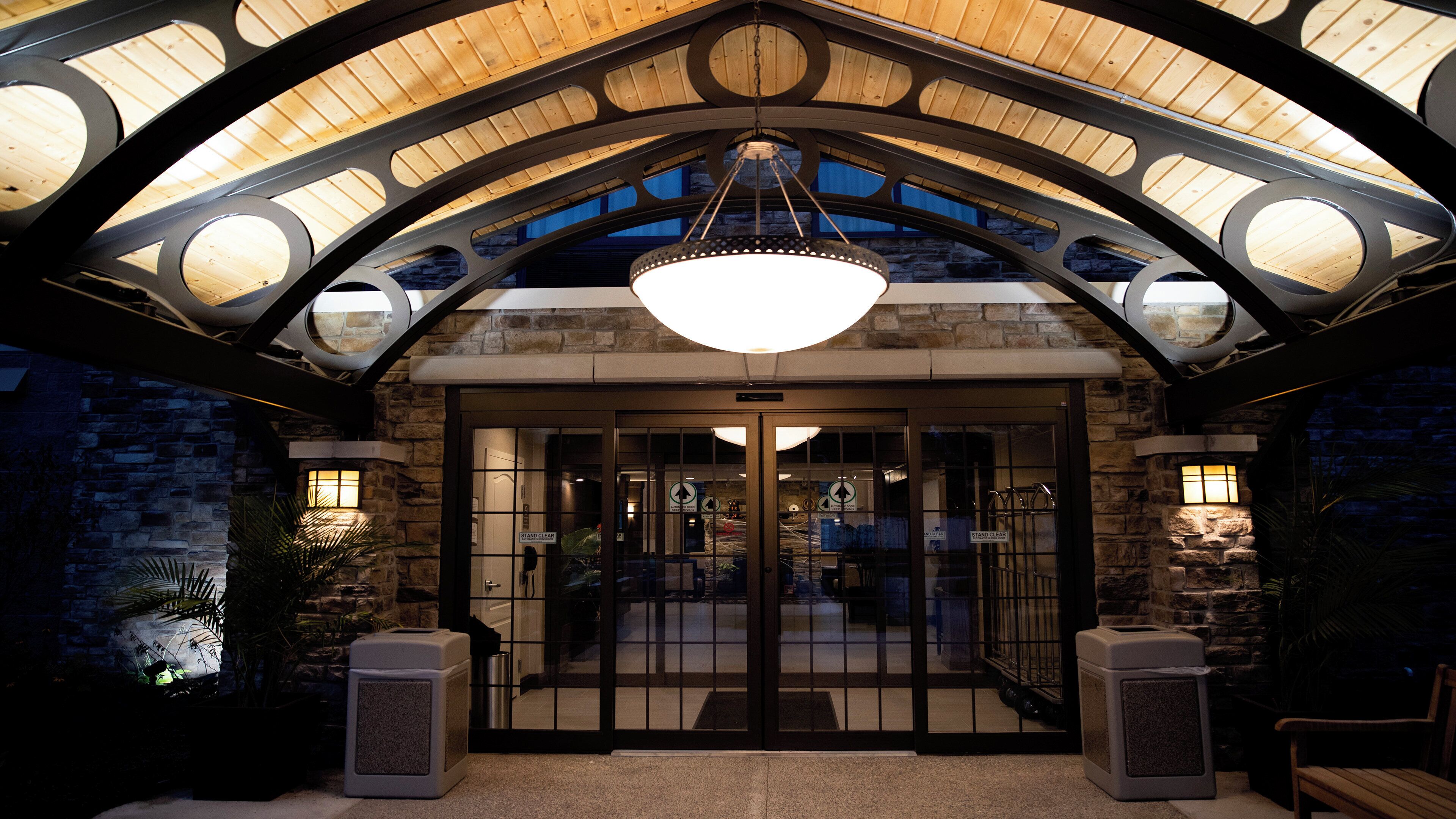 Entrada de un hotel con techo de madera, una lámpara de araña grande y paredes de piedra.
