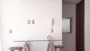 Une cuisine moderne dotée d’un îlot central, de deux tabourets de bar, d’un climatiseur et d’un miroir mural.