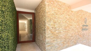 Un espace d’accueil doté d’une porte vitrée donnant sur un couloir, d’un mur végétal et d’un mur en pierre orné d’un logo.