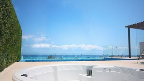 Un bain à remous offrant une vue dégagée sur l’océan et abrité dans une structure entièrement vitrée.