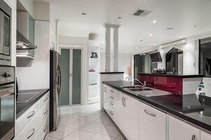 Una cocina moderna con armarios blancos, electrodomésticos de acero inoxidable y encimera negra.