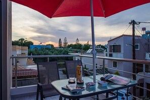 A balcony with a table, chairs, and a red umbrella.