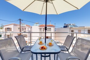 A balcony with a table, chairs, and an umbrella.