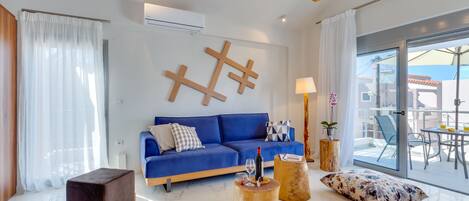 A modern living room with a blue sofa, wooden coffee table, and a glass door leading to an outdoor area.