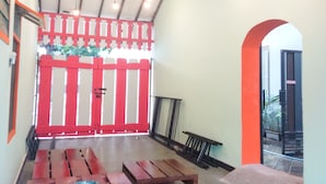 A covered outdoor seating area with wooden benches and a red door in the background.