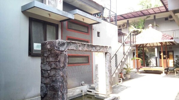 A building with a stone pillar, a staircase, and a small pool area.