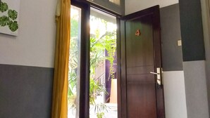 A room with a bed, a door, a curtain, and a wall-mounted air conditioner.
