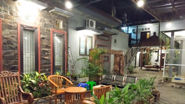 An outdoor patio area with stone walls, wooden furniture, and potted plants.