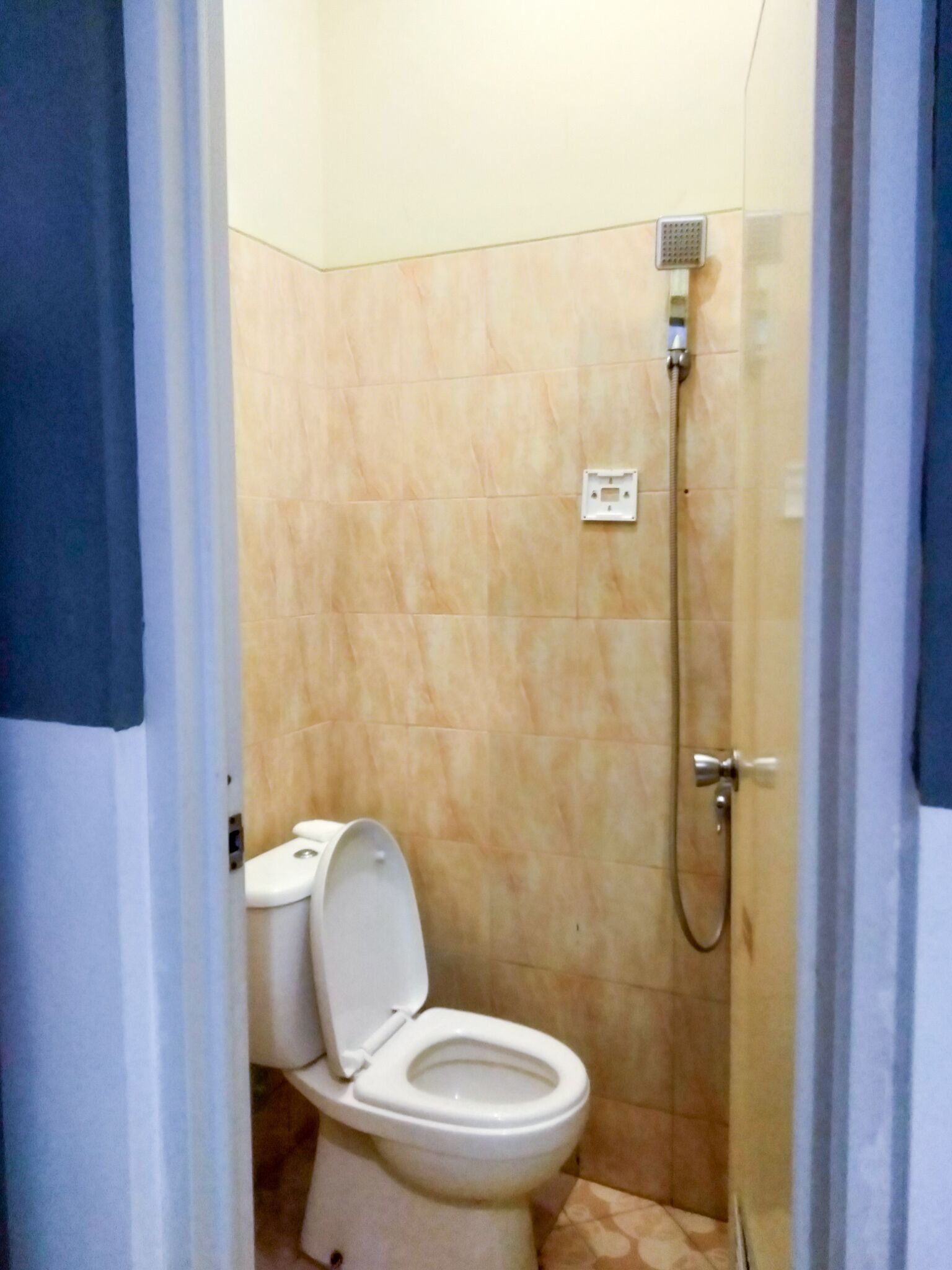 Un baño pequeño con inodoro, ducha y suelo de baldosas.