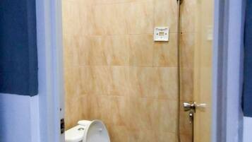 Un baño pequeño con inodoro, ducha y suelo de baldosas.