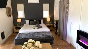 A modern bedroom with a large bed, bedside tables, a TV, and a fireplace. - Phillip Island Nature Resort (Cowes)