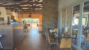A spacious restaurant with a long counter, wooden flooring, stone walls, and large windows. - Phillip Island Nature Resort (Cowes)
