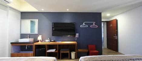Une chambre d’hôtel avec deux lits, un bureau avec un lavabo, une télévision et une armoire.
