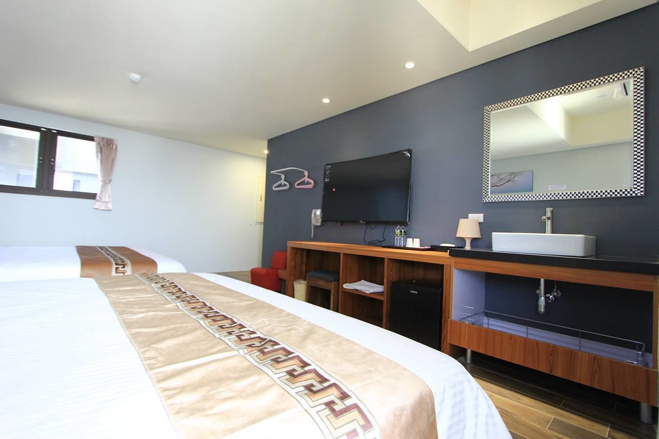A hotel room with a bed, a TV, a sink, and a mirror.