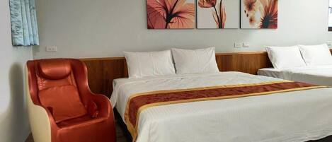 A hotel room with a bed, a massage chair, and three floral wall art pieces.