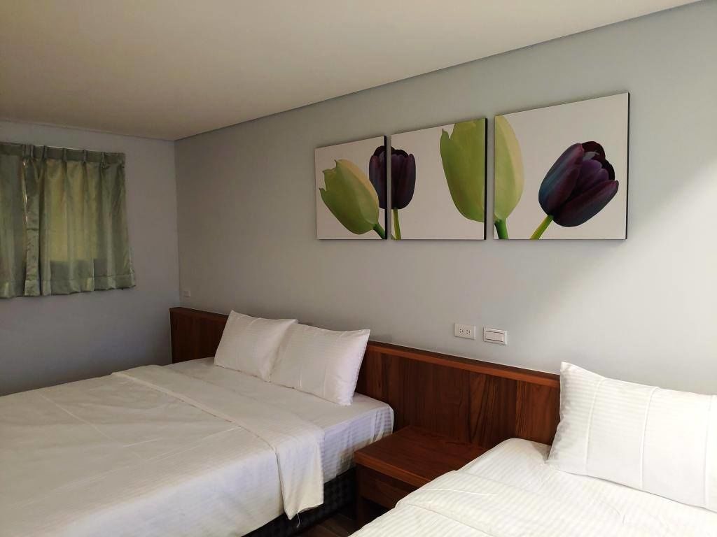 A hotel room with two beds, a wooden headboard, and a wall-mounted painting of tulips.