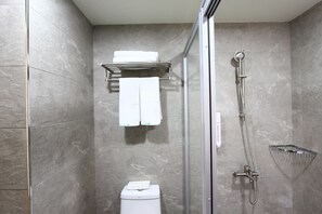 A modern bathroom with a glass shower enclosure, a toilet, and a towel rack with two white towels.