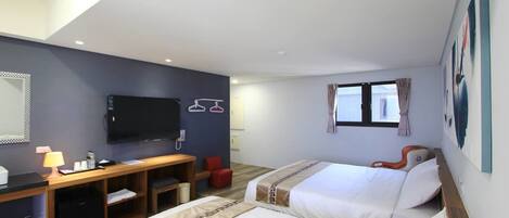 A hotel room with two beds, a desk, a TV, and a window with curtains.