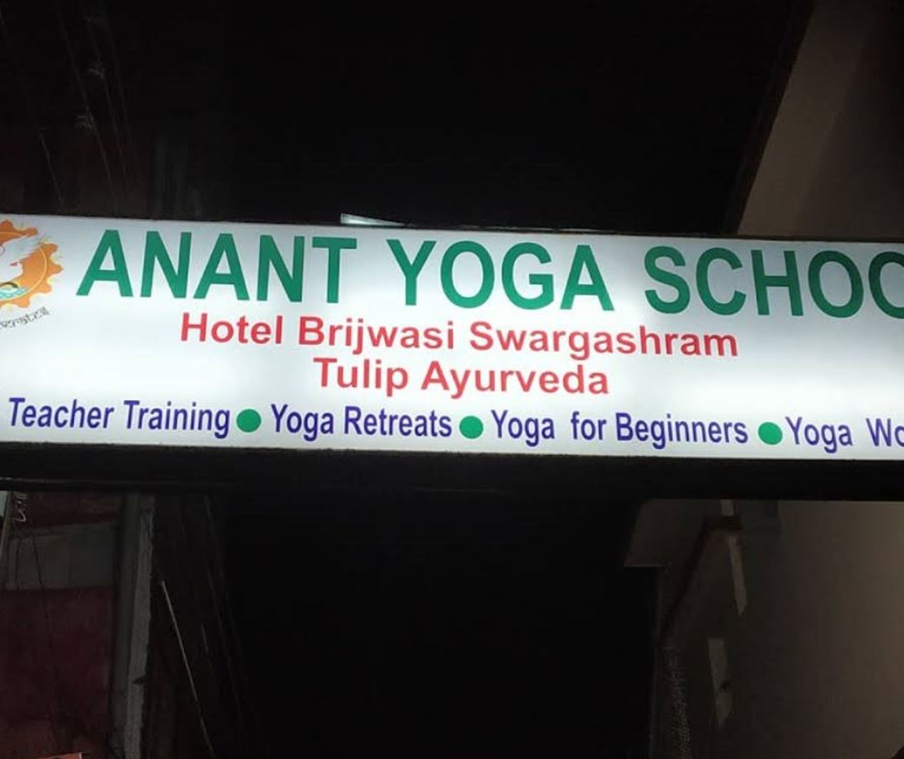 Letrero de la Escuela de Yoga Anant publicitando servicios como formación de profesores, retiros de yoga y yoga para principiantes.