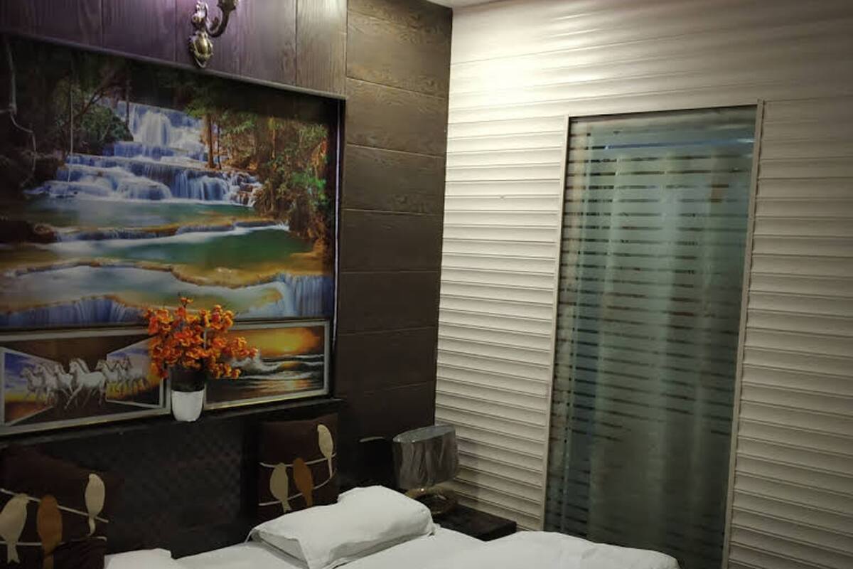 Quarto de hotel com cama, pintura de uma cascata e janela com persianas.
